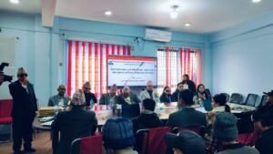 बायाँबाट दायाँतर्फ: सङ्घका निर्देशक अमृत राई मञ्चबाट उद्घोषणा गरिरहनुभएको दृश्य। अगाडि ड्यासमा प्रमुख अतिथि तथा अन्य अतिथिगणले आसन ग्रहण गर्नुभएको छ। पृष्ठभूमिमा डिजिटल ब्यानर प्रदर्शित भइरहेको छ भने सभाहलमा उपस्थित सम्पूर्ण सहभागीहरू कार्यक्रमतर्फ ध्यान केन्द्रित गरिरहेका देखिन्छन्।