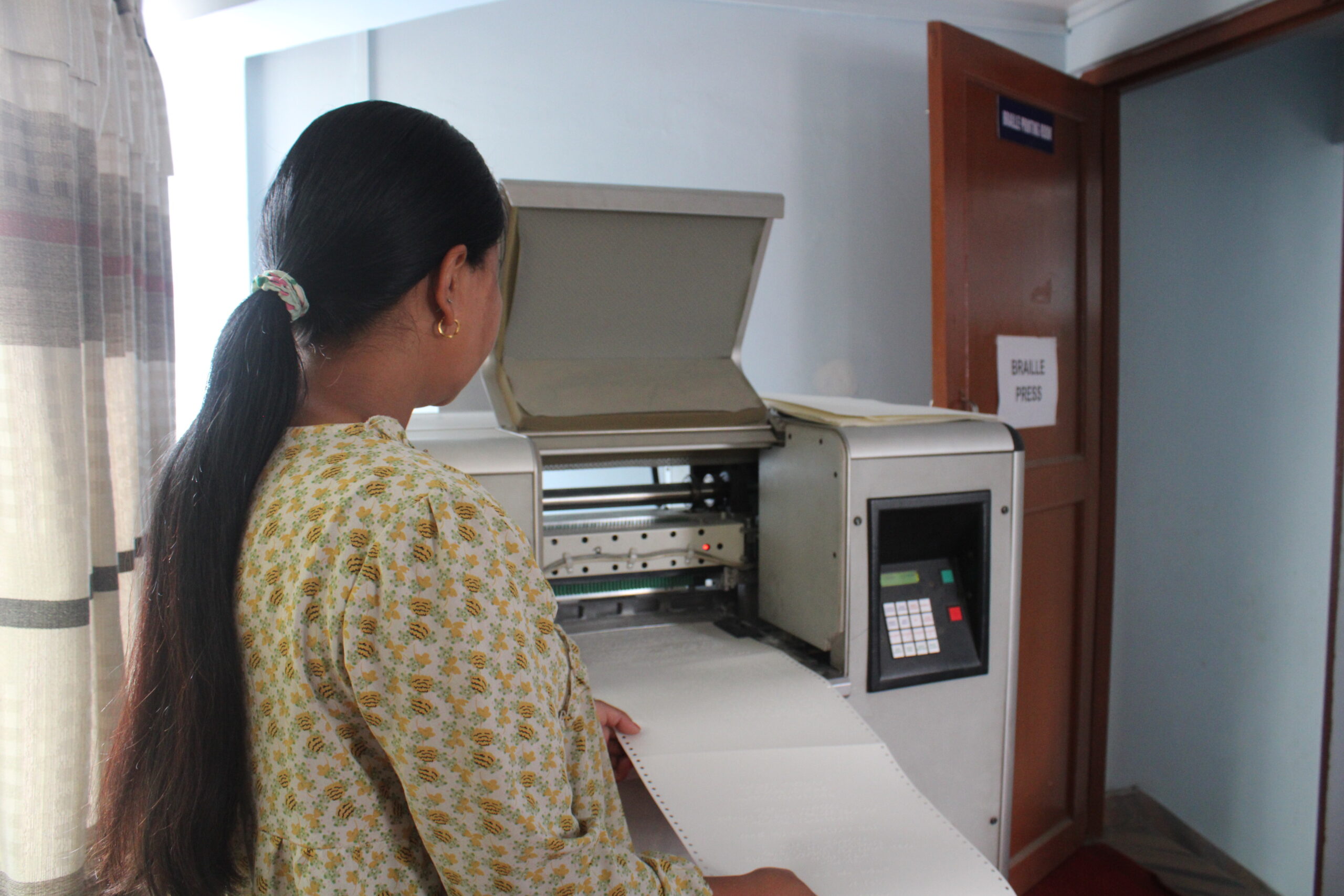 A woman operating a Braille press
