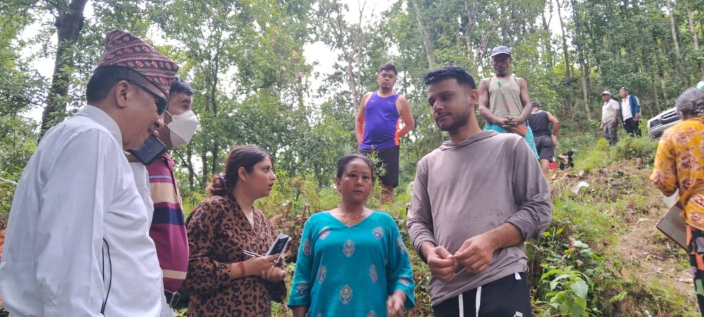 An outdoor wooded setting featuring a group of individuals( Mr Khom, Mr. Amrit, Mr. Bhusan Raut (Executive Director of PFPID) and Ms. Suyasha Adhikari (Program officer of NAB)  gathered together for a field or site visit, with a survivor of Betrawati engaged in conversation and discussion.